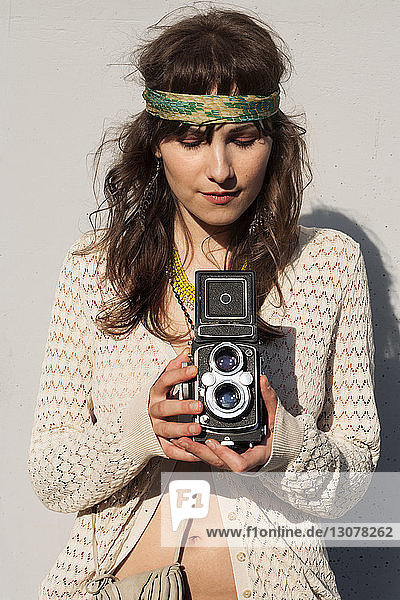 Junge Frau fotografiert durch eine Oldtimer-Kamera im Freien