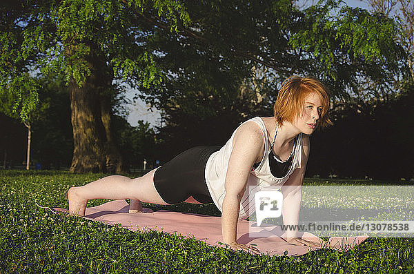 Frau praktiziert Yoga auf Übungsmatte im Park