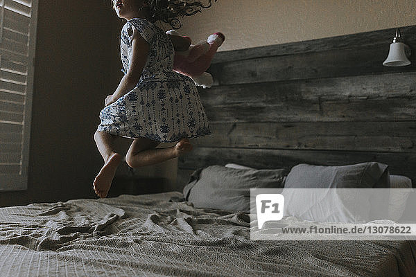 Fröhliches Mädchen springt zu Hause aufs Bett