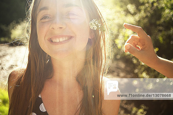Lächelndes Mädchen mit Blumen im Wald an einem sonnigen Tag