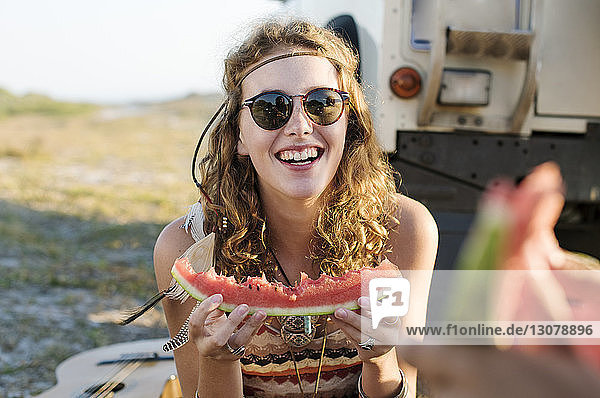 Glückliche Frau isst Wassermelone am Strand