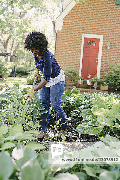 Frau benutzt Gartengabel bei der Gartenarbeit