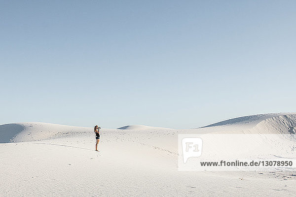 Side view of woman standing at White Sands National Monument against clear sky