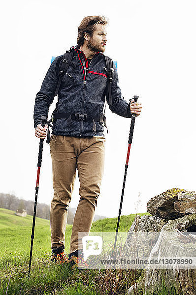 Male hiker walking on mountain against clear sky