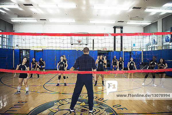 Männlicher Trainer unterrichtet Übung für weibliche Volleyballmannschaft