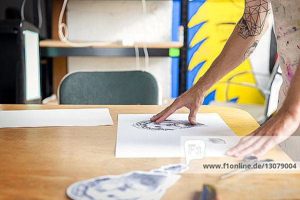 Beschnittenes Bild eines Arbeiters mit Skizze an der Werkbank in der Werkstatt