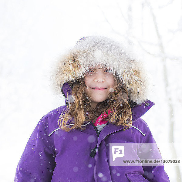 Niedrigwinkel-Porträt eines lächelnden Mädchens in warmer Kleidung  das im Winter gegen den Himmel steht