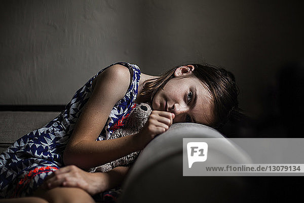 Portrait of girl resting head on sofa in darkroom