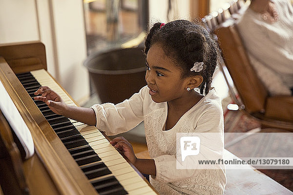 High angle view of girl playing piano in living room