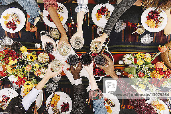 Overhead view of friends toasting drinks at table
