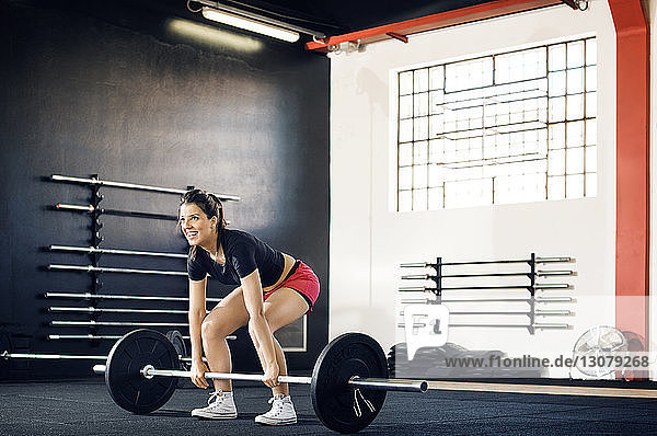 Happy woman lifting barbell in gym