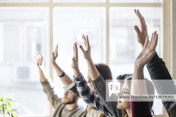 Students raising hands during lesson in classroom