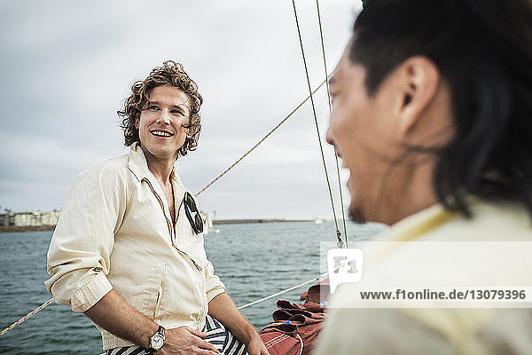 Glücklicher Mann schaut weg  während er mit einem Freund auf einem Segelboot reist