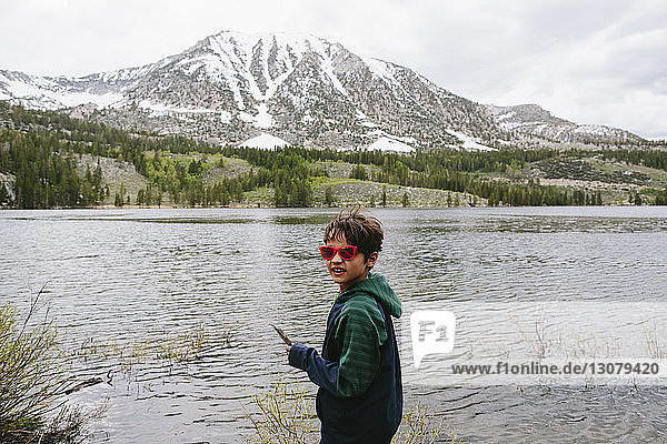 Portrait of boy in sunglasses standing by lake against mountains at Inyo National Forest