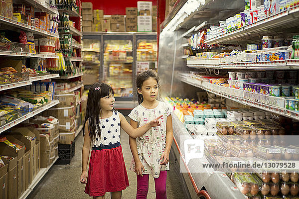 Mädchen schauen sich verschiedene Produkte in den Regalen des Supermarktes an