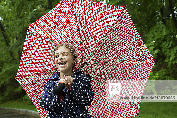 Girl laughing while holding umbrella at park