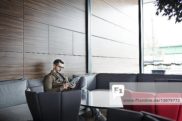 Businessman using tablet while sitting on sofa in restaurant