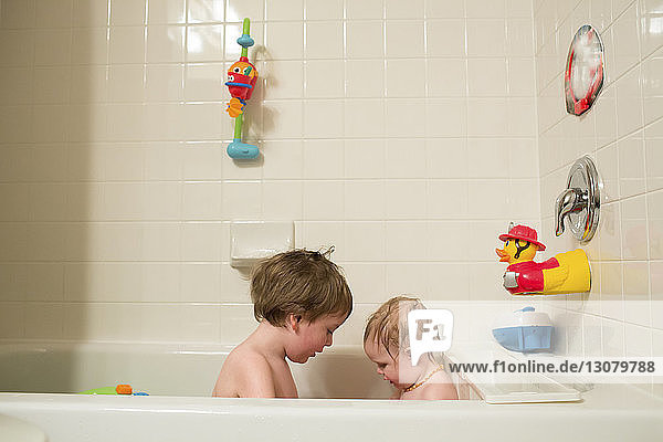 Siblings sitting in bathtub at home