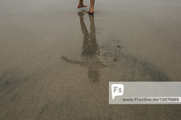 Niedriger Abschnitt einer Frau  die auf nassem Sand am Strand steht