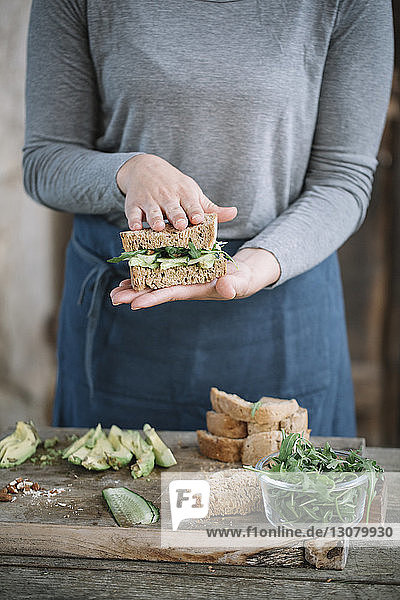 Mitschnitt einer Frau  die zu Hause auf einem Holztisch ein Sandwich macht