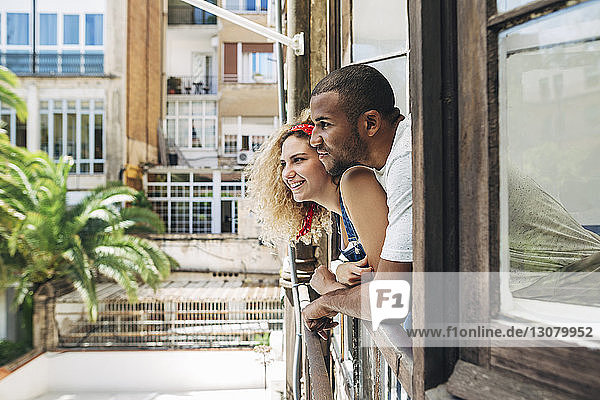 Glückliches Paar schaut durchs Fenster  während es zu Hause steht