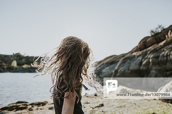 Mädchen schüttelt den Kopf  während sie am Seeufer vor klarem Himmel steht