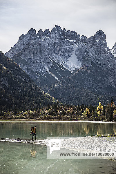 Seitenansicht eines Mannes  der im Winter am Seeufer gegen Berge läuft