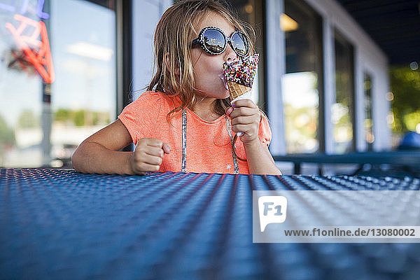 Mädchen mit Sonnenbrille isst Eis in Eisdiele