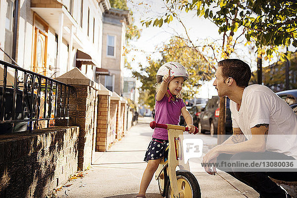 Father looking at girl pointing while sitting on bicycle