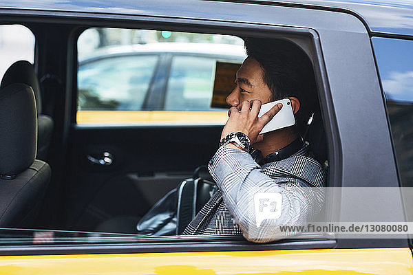 Geschäftsmann spricht mit einem Smartphone  während er im Taxi sitzt