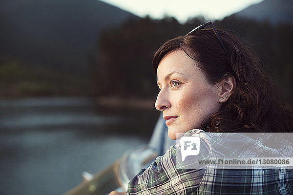 Thoughtful woman looking away while standing by lake