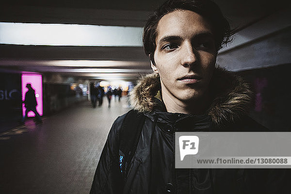 Nahaufnahme eines nachdenklichen jungen Mannes in warmer Kleidung  der auf einen U-Bahn-Gang in der Stadt schaut