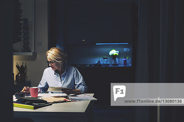 Geschäftsfrau nutzt Technologien  während sie am Schreibtisch im Heimbüro sitzt