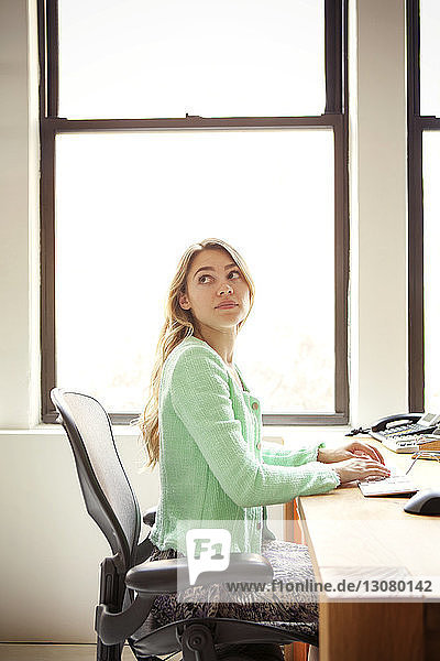 Geschäftsfrau sitzt am Büroschreibtisch am Fenster
