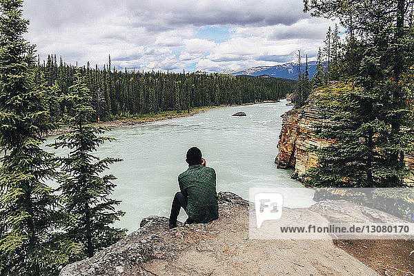 Man looking at view while sitting on cliff at Jasper National Park