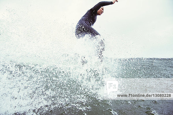Side view of determined woman surfing on sea against sky