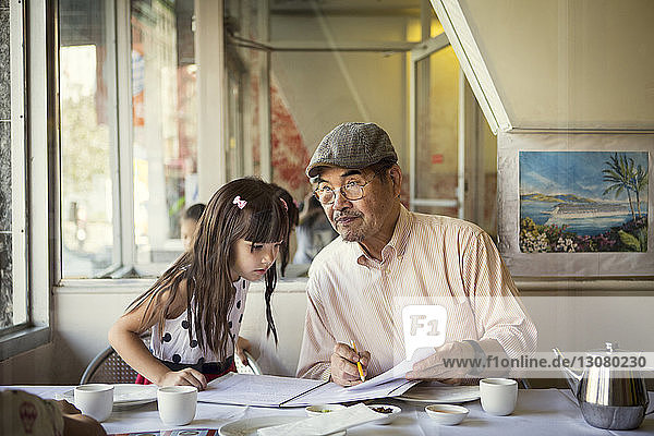 Großvater unterrichtet Enkelin  während er im Restaurant sitzt