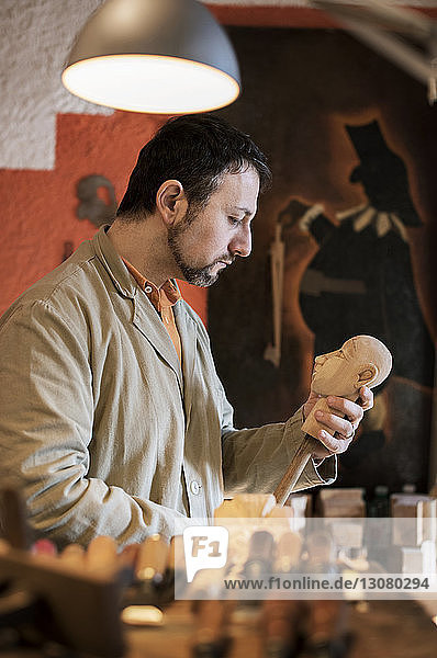 Herstellung einer Holzfigur durch einen Mann in einer Werkstatt