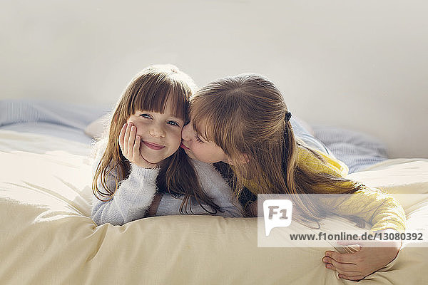 Mädchen küsst Schwester beim Entspannen zu Hause im Bett