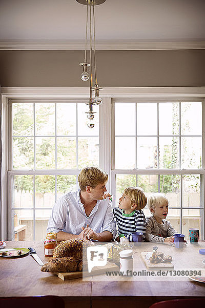 Vater und Söhne essen am Tisch vor dem Fenster