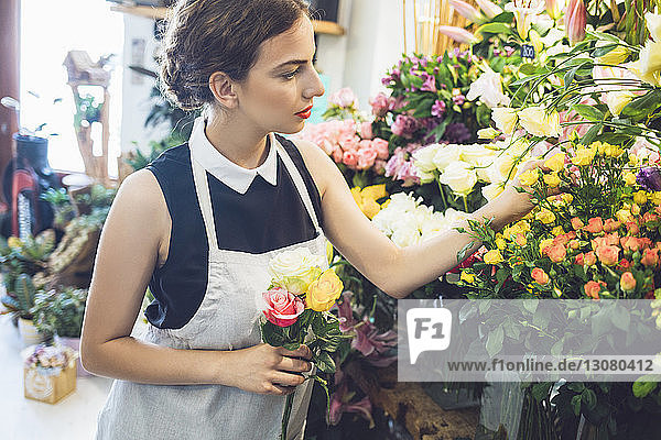 Floristin pflückt im Geschäft Rosen aus Vasen