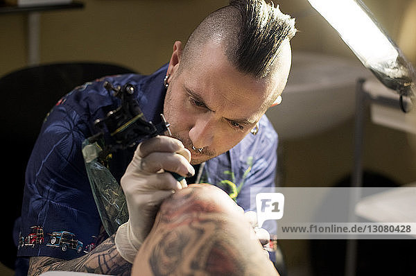 High angle view of man tattooing client at studio