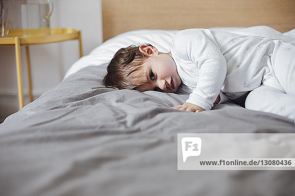 Portrait of cute baby boy lying in bed at home