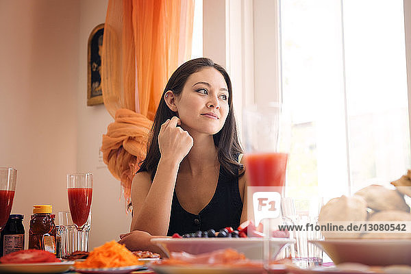 Lächelnde Frau beim Essen  während sie zu Hause sitzt