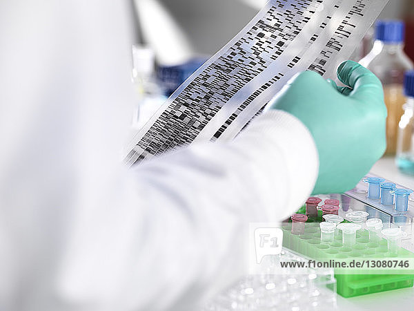 Nahaufnahme eines Wissenschaftlers  der DNA-Gel nach Proben für Labortests in der Hand hält