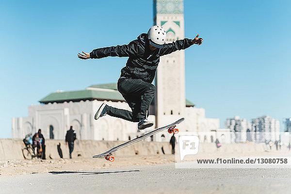 Mann führt Stunt beim Skateboardfahren gegen die Moschee Hassan II aus