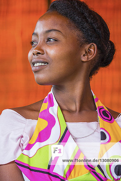 Nachdenkliche junge Afrikanerin schaut weg gegen orangefarbene Wand