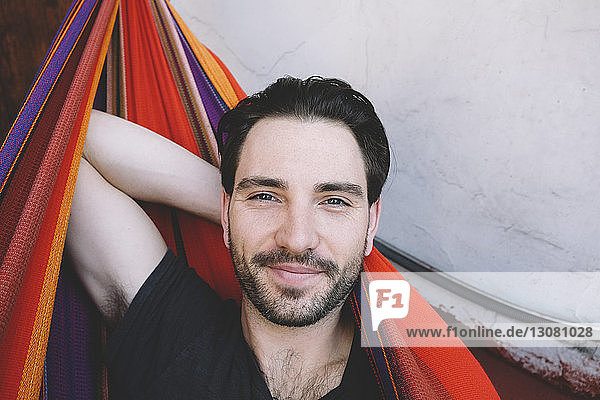 Portrait of confident man with hand behind head relaxing in hammock