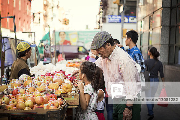 Großvater mit Enkelinnen beim Obstkauf am Marktstand