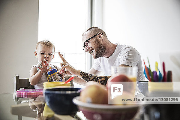 Father gesturing while teaching daughter at breakfast table